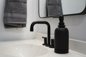 A modern bathroom with a white sink, black faucet, and a black soap dispenser. - Modern Lakeside Family Fun Cabin (Pinetop-Lakeside)