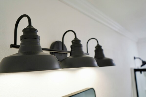 A row of three black wall-mounted lamps with curved arms, evenly spaced on a white wall. - Modern Lakeside Family Fun Cabin (Pinetop-Lakeside)