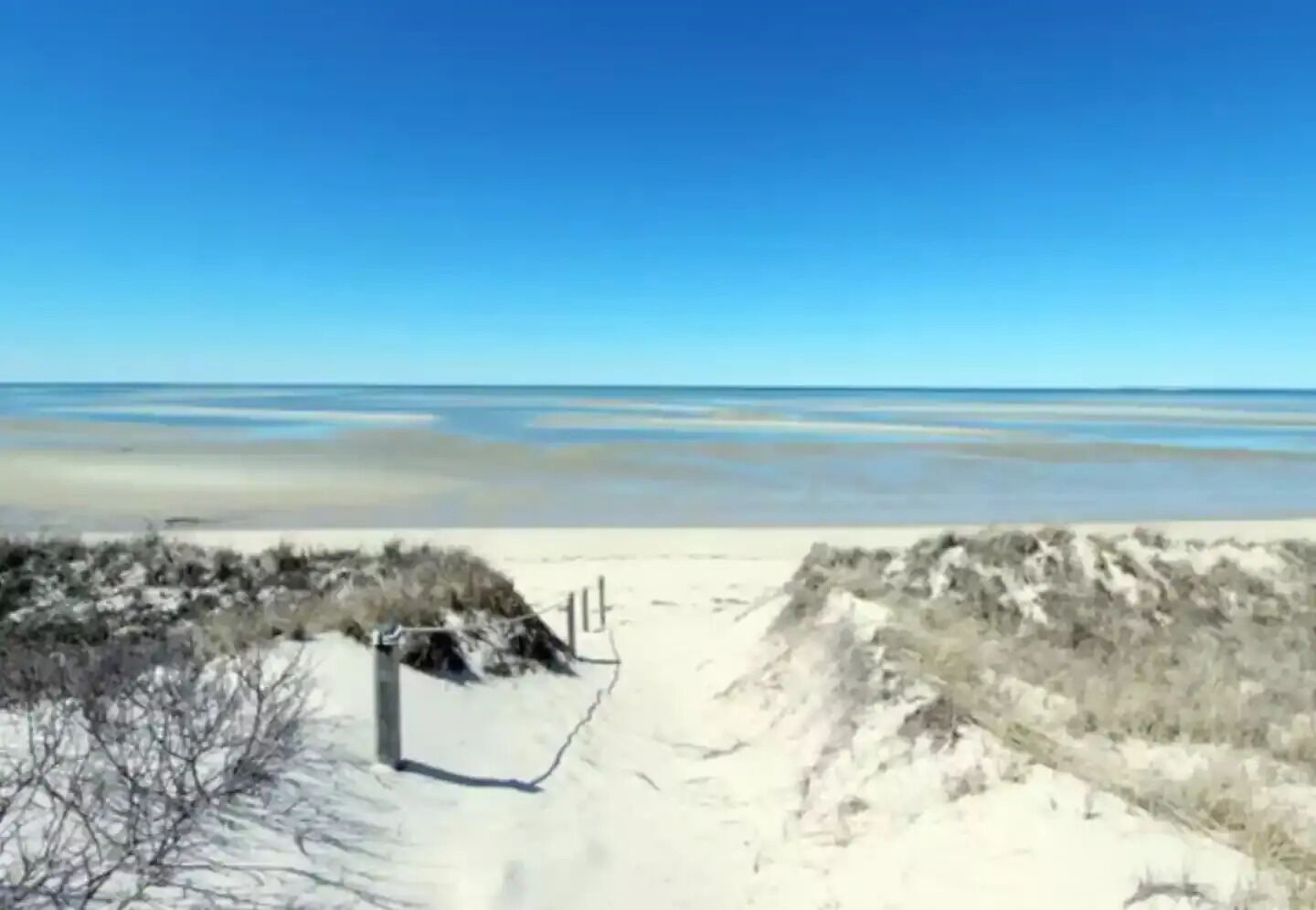 A sandy beach with dunes and a clear sky.