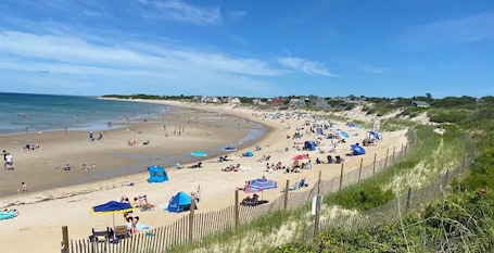 Una playa con gente, tiendas de campaña y sombrillas.