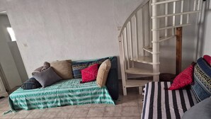 A room with a bed, a sofa, a staircase, and a tiled floor. - Maison de Village (Puimisson)