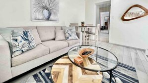 Un salon moderne avec un canapé, une table basse en verre et un tableau accroché au mur.