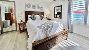 Une chambre à coucher avec un lit, une table de chevet, une lampe et une œuvre d’art accrochée au mur.
