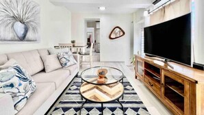 Un salon avec un canapé, une table basse, un téléviseur et un tapis à motifs.
