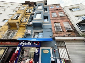 A multi-story building with a variety of architectural styles, including a blue storefront with mannequins displaying clothing.