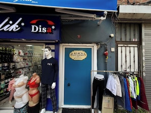 A storefront with a blue awning, a mannequin dressed in casual attire, and a display of clothing items.