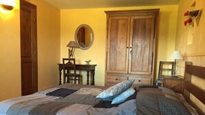 A bedroom with a bed, wooden wardrobe, a desk with a lamp, and a mirror on the wall. - Le Vernay - Pierreclos (PIERRECLOS)