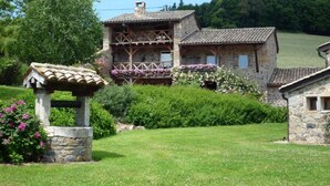 A stone building with a balcony, surrounded by lush greenery and a well-maintained lawn. - Le Vernay - Pierreclos (PIERRECLOS)