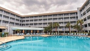 Un hôtel doté d’une grande piscine, de nombreux balcons et d’un espace salon couvert.