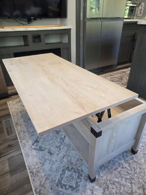 A kitchen with a wooden table, a television, and a refrigerator.