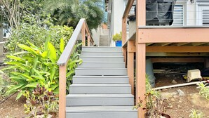 A staircase leading to a wooden deck with a railing, surrounded by potted plants and a garden. - A Private Space by Villa Sunbeam. (St. Thomas)