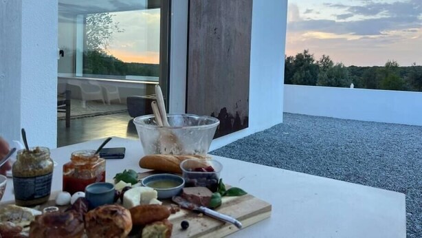 Un balcon avec une table dressée pour un repas, offrant une vue sur un paysage magnifique.