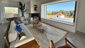 Un salon spacieux doté d’une grande fenêtre, d’un canapé, d’une table basse et d’une cheminée.