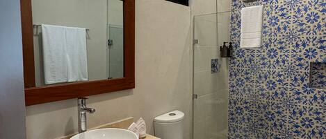 A bathroom with a large mirror, a sink, a toilet, and a shower.