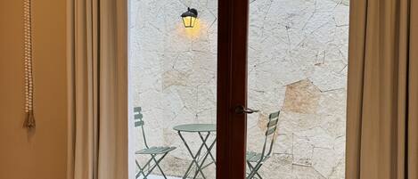 Une pièce dotée d’une grande porte-fenêtre coulissante qui donne sur un espace extérieur agrémenté d’un mur en pierre et d’une table avec des chaises.