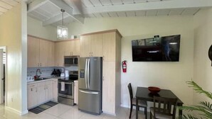 A modern kitchen with stainless steel appliances, a dining area with a table and chairs, and a flat-screen TV mounted on the wall. - Angie's Sunset View (St Thomas)