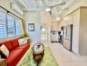 Ein modernes Wohnzimmer mit einem roten Sofa, einem Glastisch und einer Küchenzeile mit Edelstahlgeräten.