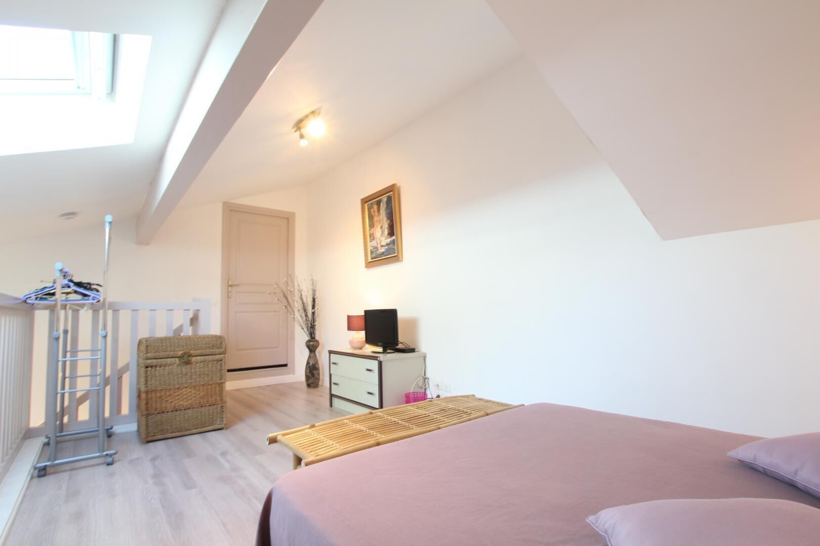 A bedroom with a bed, a desk with a computer, a chair, a wardrobe, and a window.