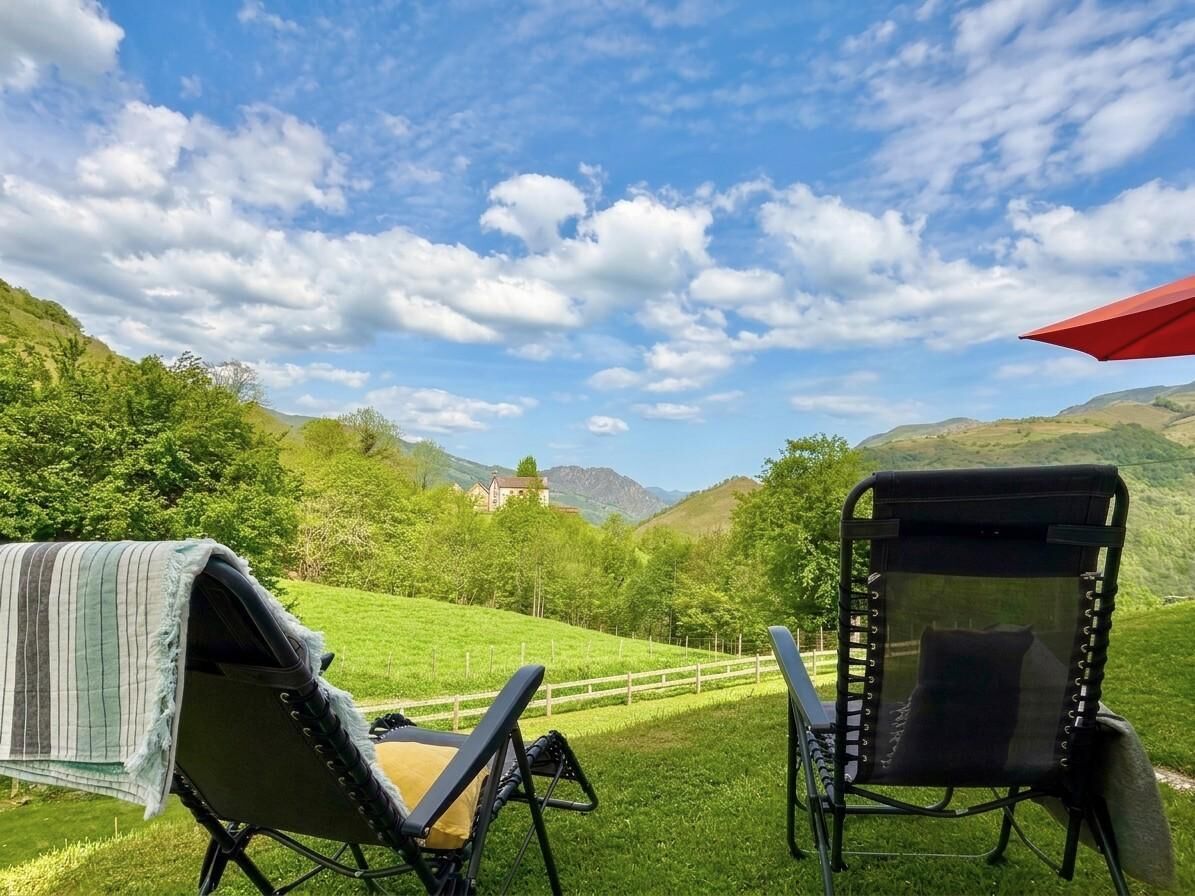 Zwei Gartenstühle mit Blick auf eine grüne Landschaft und ein entferntes Gebäude.