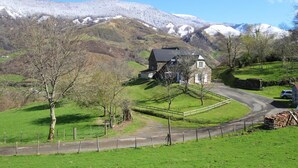 A stone house with a sloped roof, surrounded by a fenced yard, set against a backdrop of snow-capped hills. - Artegia - Sainte-engrace (SAINTE-ENGRACE)