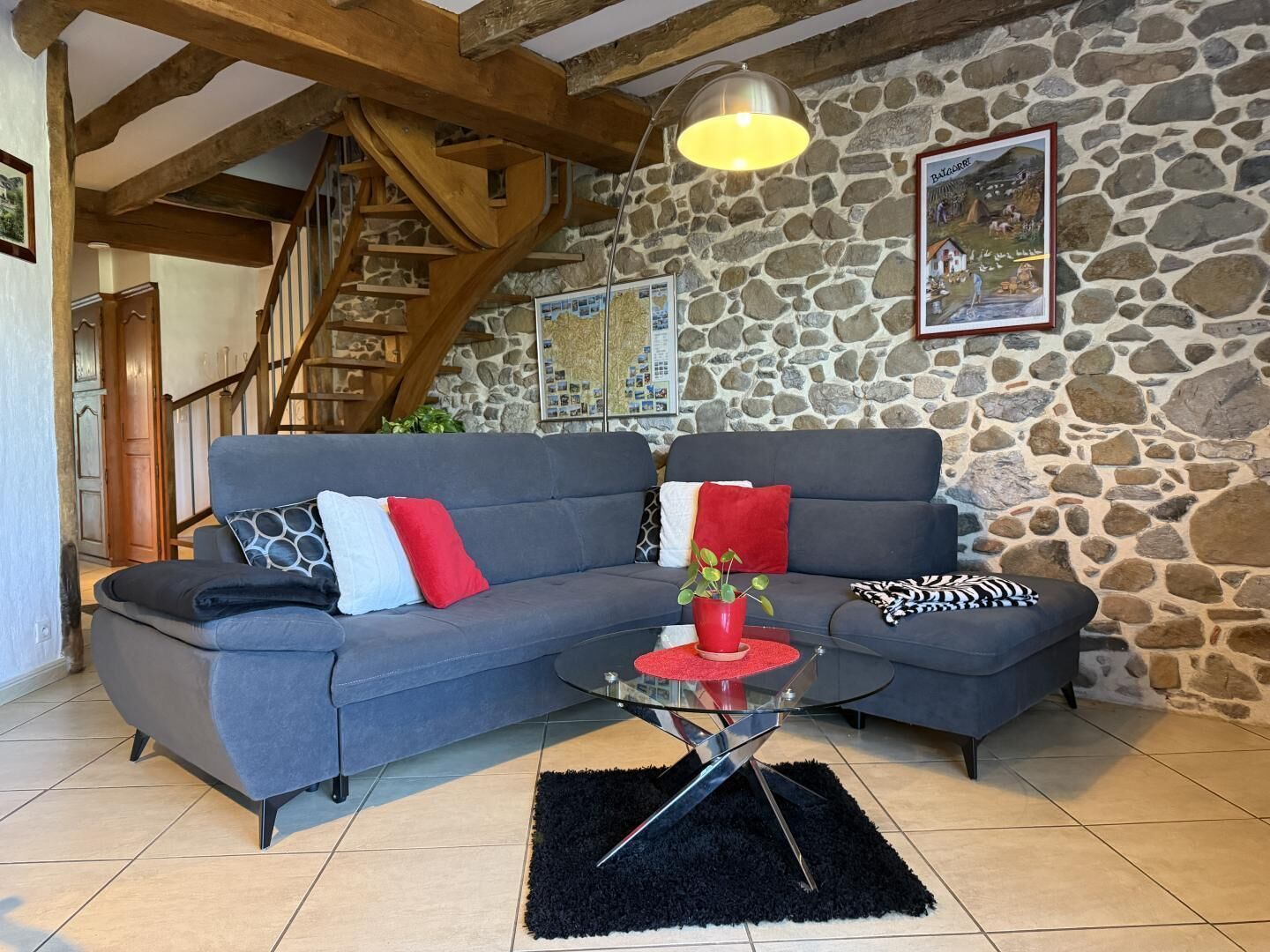 A cozy living room with a stone wall, a blue sofa, and a wooden staircase.