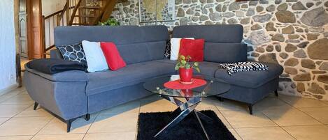 A cozy living room with a stone wall, a blue sofa, and a wooden staircase.