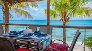 A table set for dining with a view of the ocean and a ship in the distance.