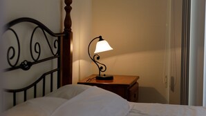 A bed with a wooden headboard, a bedside table with a lamp, and a wall-mounted telephone. - Luxury Villa (Agia Thekla)