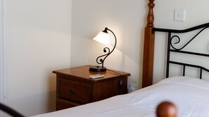 A neatly made bed with a wooden headboard, a bedside table with a lamp, and a small drawer. - Luxury Villa (Agia Thekla)