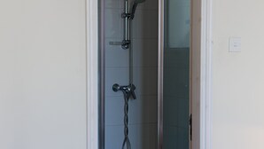 A bathroom with a glass-enclosed shower, a toilet, and a checkered floor. - Luxury Villa (Agia Thekla)