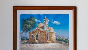 A framed painting of a church with a bell tower, a tree, and a clear sky. - Luxury Villa (Agia Thekla)