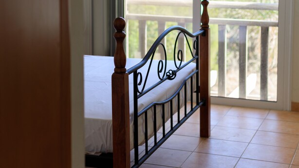 A bedroom with a bed, a balcony with a railing, and a view of greenery outside. - Luxury Villa (Agia Thekla)