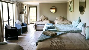 A hotel room with two beds, a sofa, a chair, and a large window.