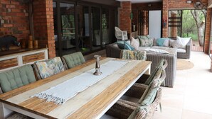An outdoor patio with a wooden table, wicker furniture, and a brick wall.