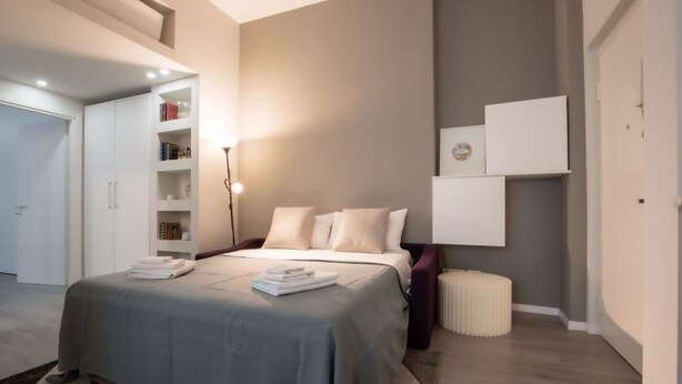 Une chambre à coucher moderne avec un lit, des tables de chevet, une armoire et une lampe de chevet.