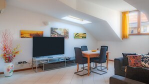 A modern living room with a flat-screen TV, dining table, chairs, a sofa, and artwork on the walls. - ASIAGO, 41 · Quartiere Gorla, verde in città (Milano)