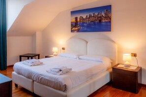 Hotelkamer met een groot bed, twee nachtkastjes, een stadslandschap op de muur en uitzicht over de stad.