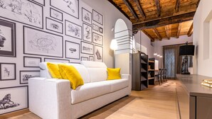 A modern living room with a white sofa, yellow cushions, and a wall adorned with framed sketches. - VIA SIMONE MAYR, 2 · Bergamo città Alta - appartamento di charme (Bergamo)