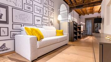 A modern living room with a white sofa, yellow cushions, and a wall adorned with framed sketches.