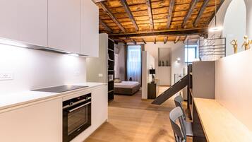 A modern kitchen with white cabinetry, a built-in oven, and a wooden ceiling.
