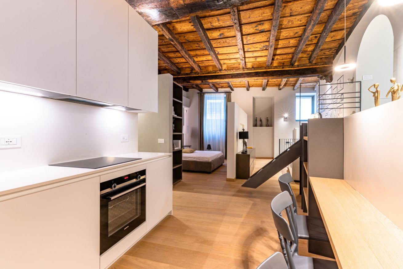 Une cuisine moderne avec des meubles blancs, un four encastré et un plafond en bois.