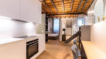 Eine moderne Küche mit weißen Schränken, einem eingebauten Backofen und einer Holzbalkendecke.