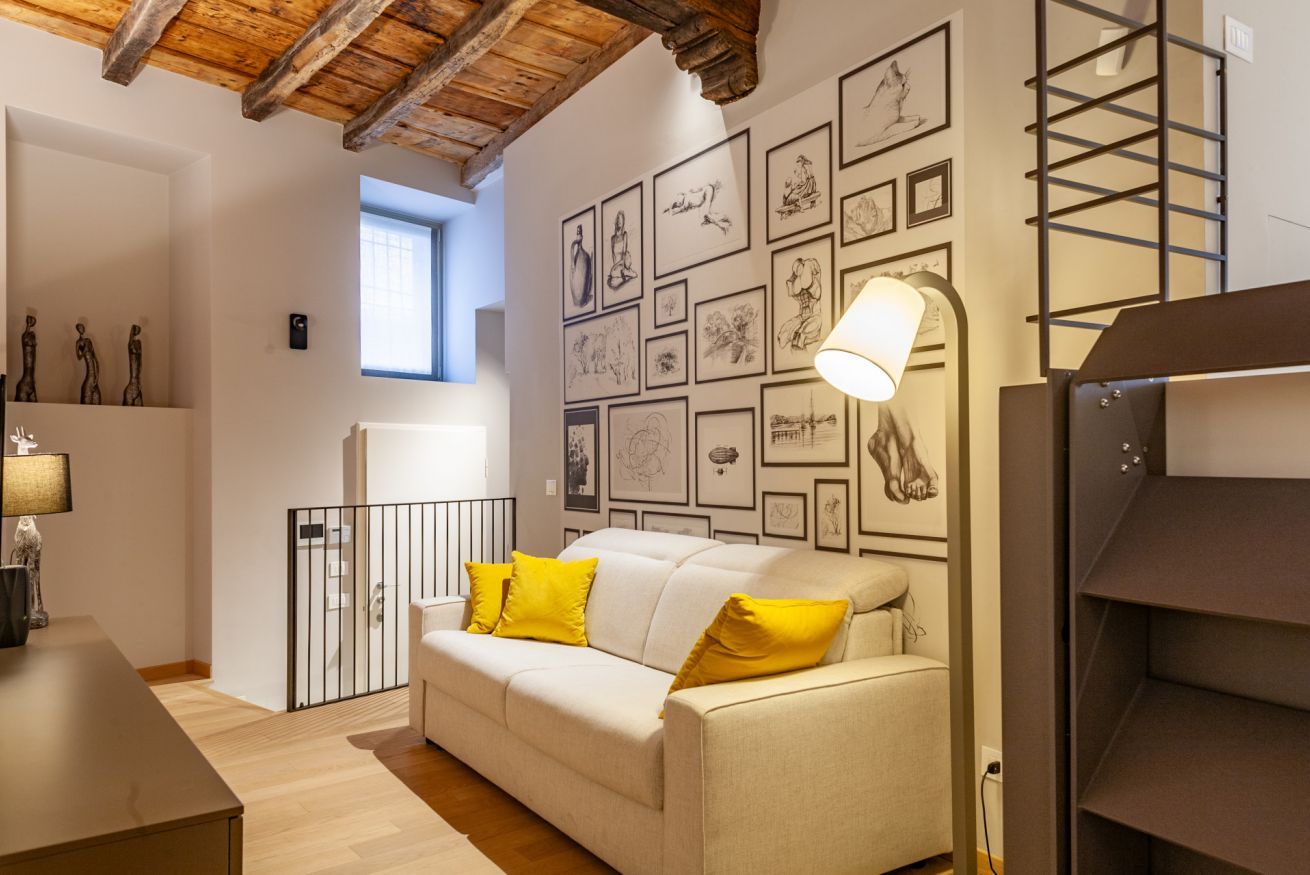 Un accogliente soggiorno con divano, lampada e parete decorata con quadri.