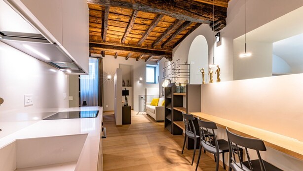 A modern kitchen with a wooden ceiling, white cabinetry, and a dining area with chairs and a table. - VIA SIMONE MAYR, 2 · Bergamo città Alta - appartamento di charme (Bergamo)