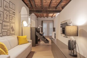 A modern living space with a staircase, a sofa with yellow cushions, a lamp, and framed artwork on the walls. - VIA SIMONE MAYR, 2 · Bergamo città Alta - appartamento di charme (Bergamo)