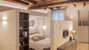 A bedroom with a bed, built-in shelving, a TV, and a lamp. - VIA SIMONE MAYR, 2 · Bergamo città Alta - appartamento di charme (Bergamo)