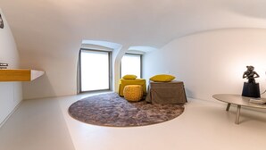A modern loft bedroom with a skylight, a round rug, a small table, and two yellow ottomans. - VIA SIMONE MAYR, 2 · Bergamo città Alta - appartamento di charme (Bergamo)