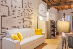 A living room with a white sofa, yellow cushions, a lamp, and framed artwork on the wall. - VIA SIMONE MAYR, 2 · Bergamo città Alta - appartamento di charme (Bergamo)