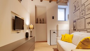 A modern living room with a flat-screen TV, a sofa with yellow cushions, a lamp, and artwork on the walls. - VIA SIMONE MAYR, 2 · Bergamo città Alta - appartamento di charme (Bergamo)