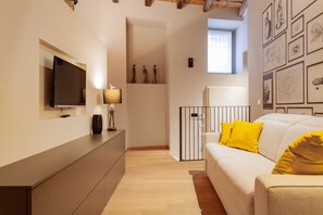 A modern living room with a flat-screen TV, a sofa with yellow cushions, a lamp, and artwork on the walls. - VIA SIMONE MAYR, 2 · Bergamo città Alta - appartamento di charme (Bergamo)